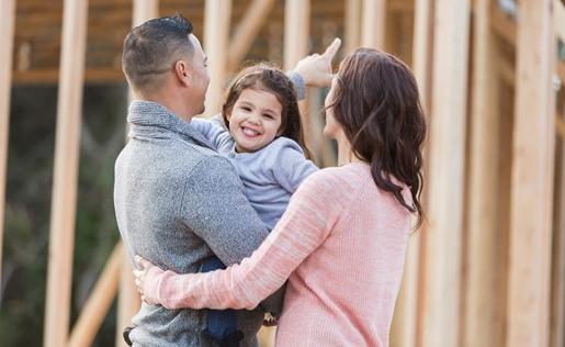 Couple and baby looking at their home being built