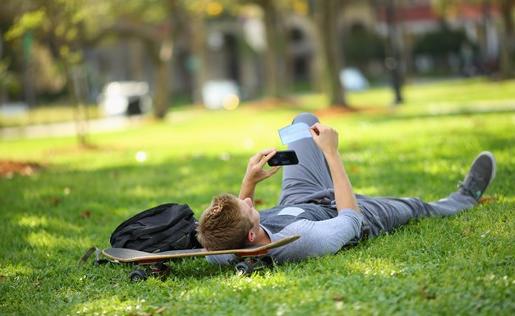 A student laying in the grass on a skate board