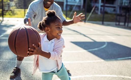 A father playing basketball with his daughter